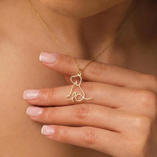 May include: A delicate gold-colored necklace featuring a minimalist outline of a dog. The pendant is suspended from a fine chain, creating a simple yet elegant design. The dog silhouette is a continuous line, showcasing a modern aesthetic.