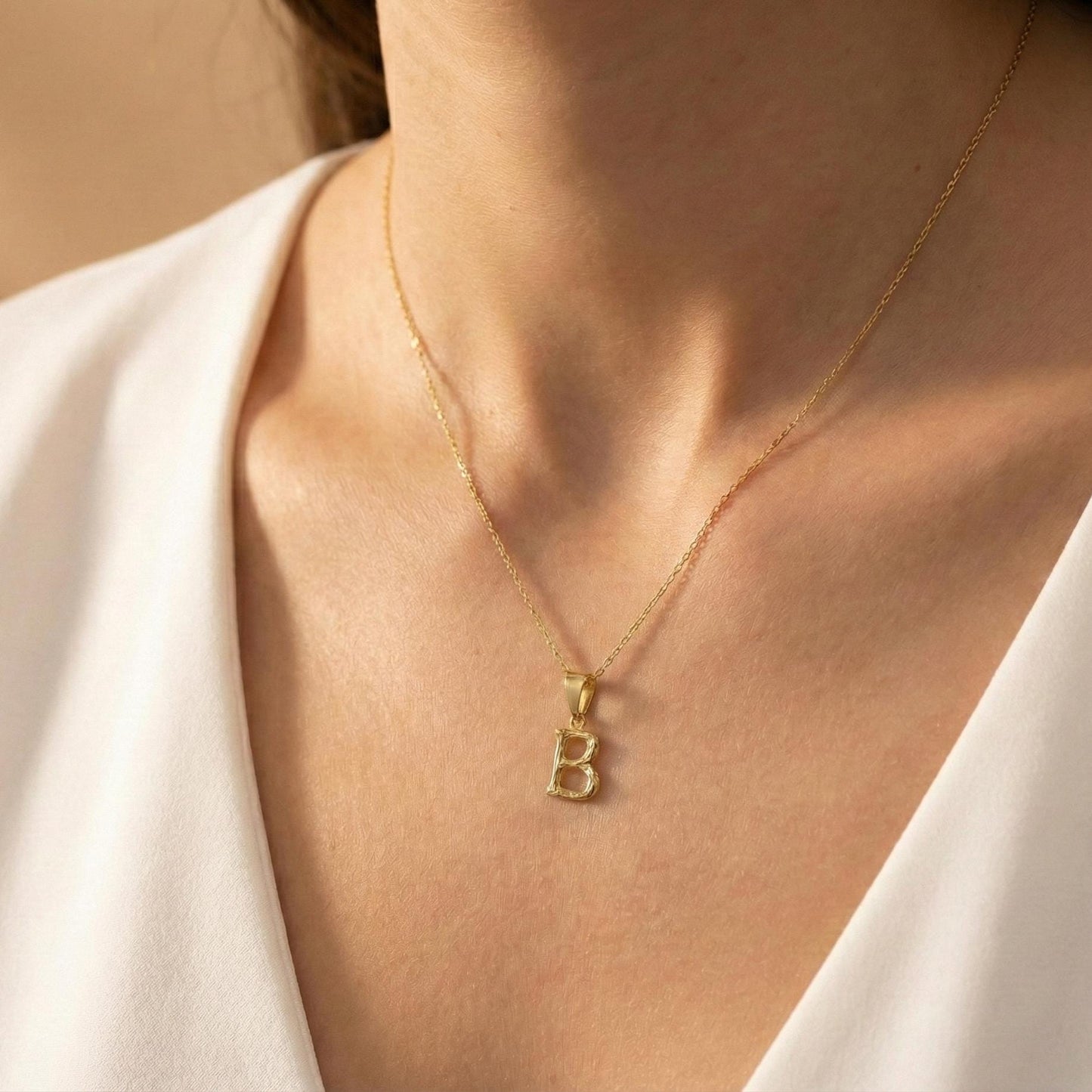 Gold color bamboo texture initial necklace letter pendant on model, minimalist personalized jewelry for mothers day gift.