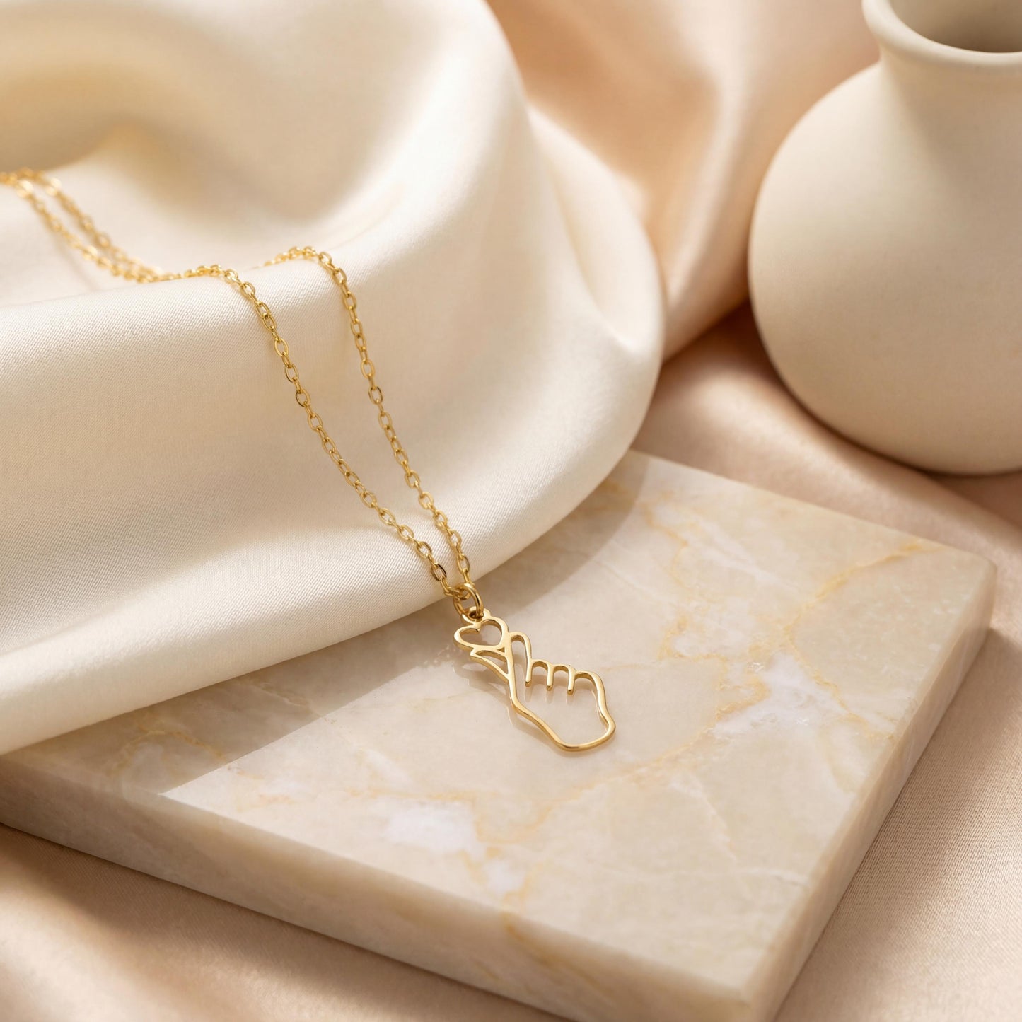 A woman wearing a dainty 14K gold minimalist Korean finger heart necklace, a delicate saranghae hand gesture pendant resting on her collarbone.