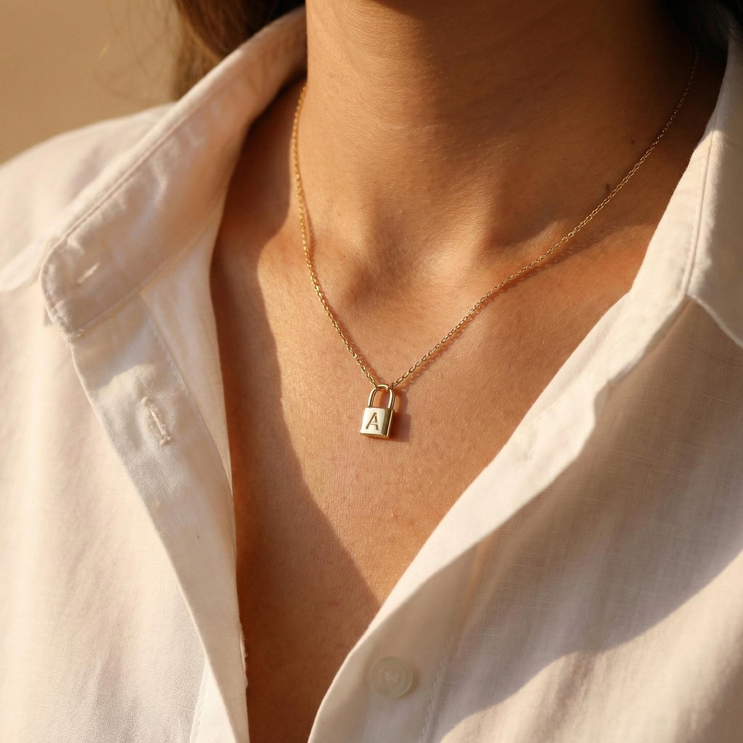 Gold padlock necklace with engraved initial letter A, dainty minimalist personalized jewelry gift for her, Mother's Day custom pendant on model.