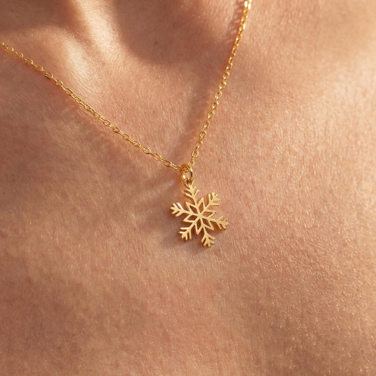 Dainty 14K gold plated snowflake pendant necklace resting elegantly on a woman's collarbone, showing a minimalist geometric jewelry design perfect for a unique Mother's Day gift or layered everyday wear.