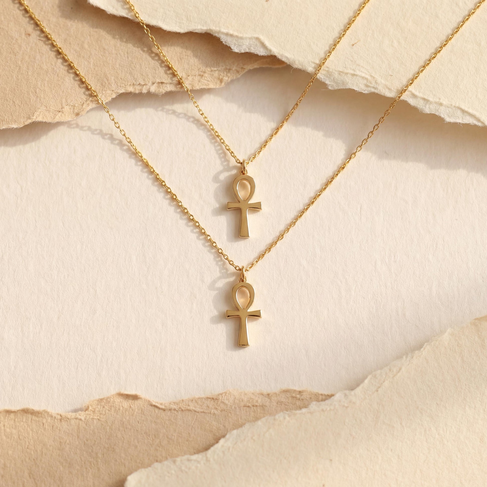 Minimalist Ankh necklace worn by a woman, dainty Egyptian cross key of life pendant resting on chest in natural sunlight, elegant everyday jewelry.