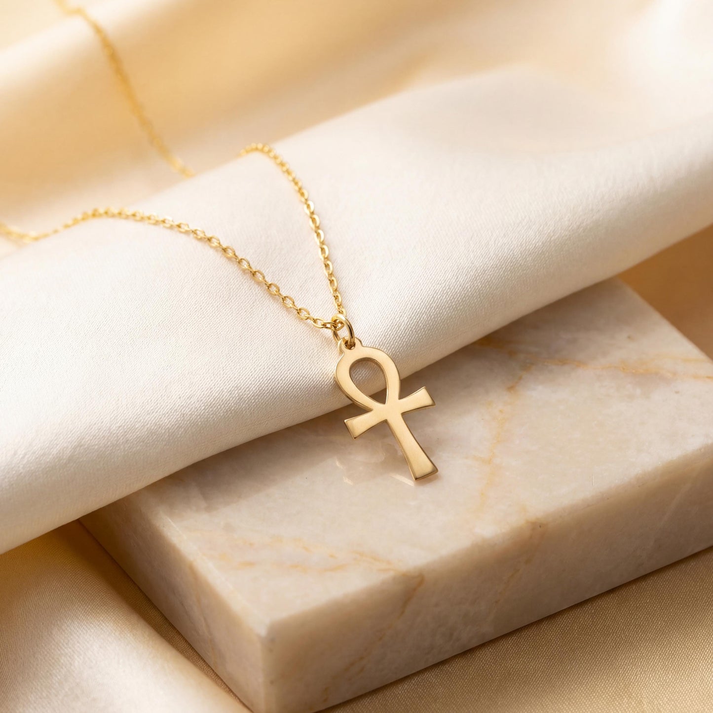 Minimalist Ankh necklace worn by a woman, dainty Egyptian cross key of life pendant resting on chest in natural sunlight, elegant everyday jewelry.