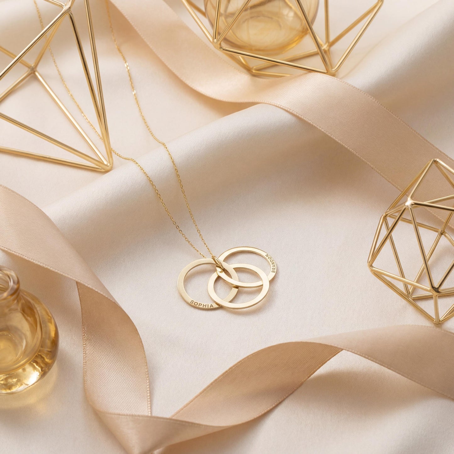 14K gold plated interlocking circle necklace featuring three beautifully intertwined rings, delicately custom engraved with the family names Sophia and Brandon, resting elegantly on a woman's collarbone.